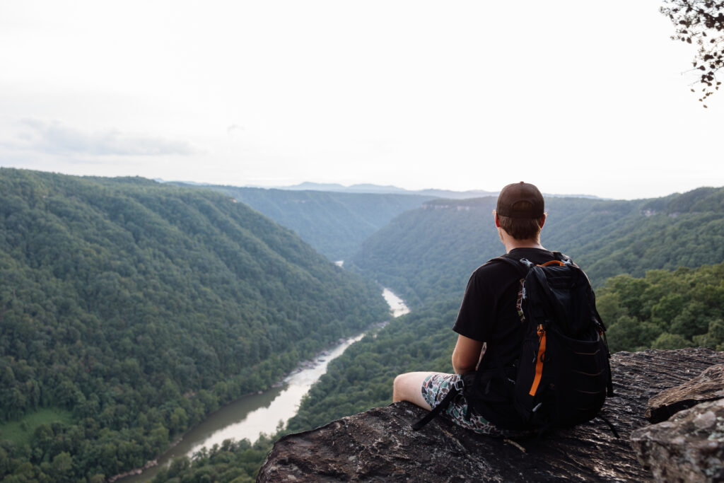 man sitting and watching sunset over a gorge