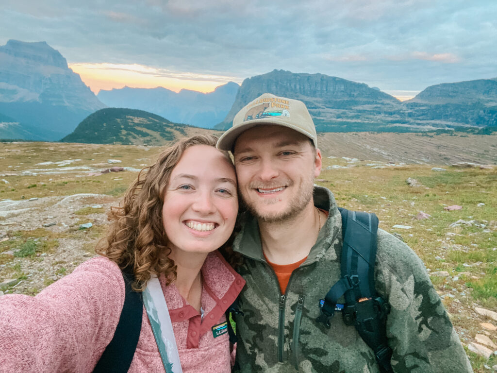 husband and wife smiling in front of a mountain range